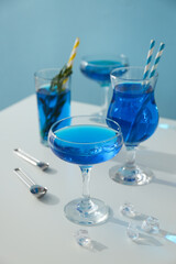 Blue drink in cocktail glasses and ice cubes on blue background, close up