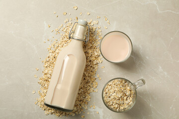 Bottle and glass with milk, oatmeal on beige background, top view
