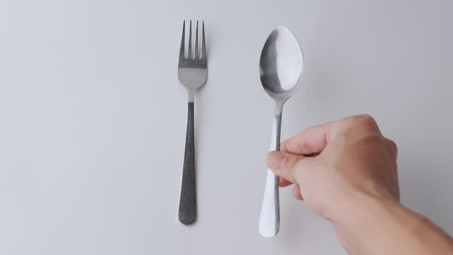 Fork and spoon being placed on a white background
