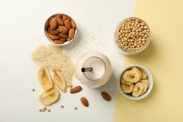 Bottle of alternative milk and herbal ingredients on light background, close up