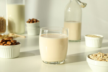 Bottles and glass of alternative milk, nuts and oatmeal on light background, close up