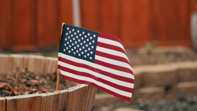 Small american flag stuck in a wooden planter in winter 