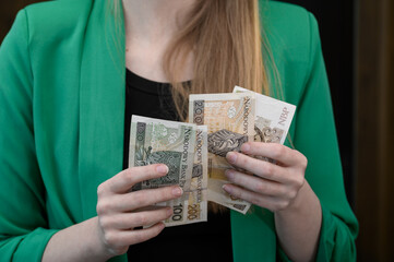 Liczyć pieniądze, polskie banknoty PLN w dłoni młodej kobiety
