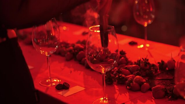 girl fumigates empty wine glasses with palo santo aroma sticks in red light