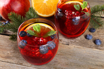 Aromatic Christmas Sangria drink in glasses, fir branches and ingredients on wooden table