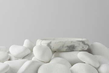 Presentation for product. Stone podium and white pebbles on light background. Space for text