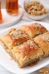 Eastern sweets. Pieces of tasty baklava and tea on white table, closeup