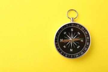 One compass on yellow background, top view and space for text. Tourist equipment