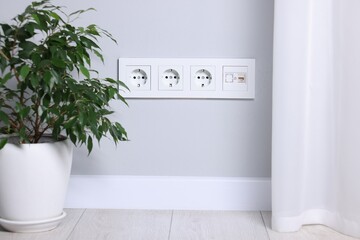 Electric power sockets on light grey wall indoors