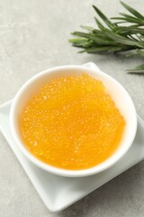 Fresh pike caviar in bowl and rosemary on light grey table, closeup