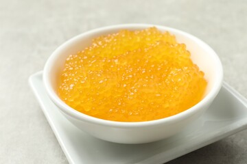 Fresh pike caviar in bowl on light grey table, closeup