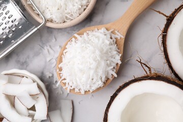 Coconut flakes, nut, grater and spoon on white marble table, flat lay