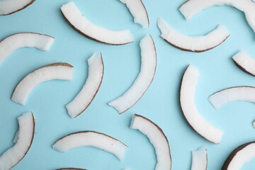 Fresh coconut pieces on light blue background, top view