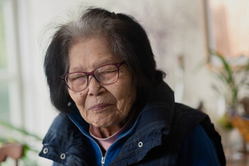 A ninety-something grandmother turns to look at the camera with a smile. She is of Ryukyuan...