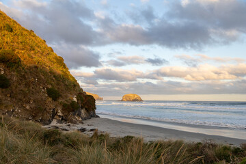 Wundersch&ouml;ner Strand im S&uuml;den von Neuseeland im Sonnenuntergang mit Wellen und Wolken