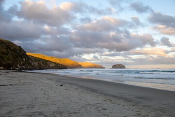Wundersch&ouml;ner Strand im S&uuml;den von Neuseeland im Sonnenuntergang mit Wellen und Wolken