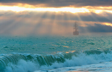 An old sailing ship in the mist sails towards the rocks - Sailing old ship in a storm sea in the background stormy clouds
