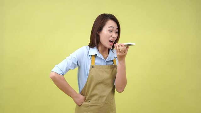 Young Asian woman wearing apron on green background