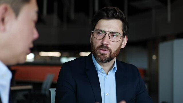 Concentrated bearded business person listening attentively to unknown man and complementing opinion. Two males exchanging entrepreneurial experience and motivating each other for developing.