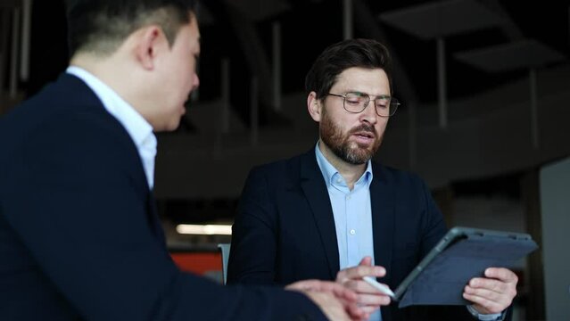 Successful company ceo checking electronic version of report from employee on probation and asking question. Strict boss in stylish suit making decision about hiring new worker depending on results.