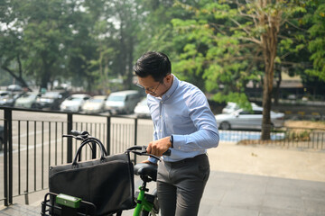 Handsome young businessman with bicycle on a city street. City life and transportation concept