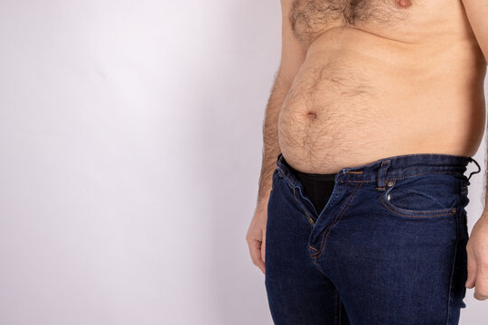 A middle aged slightly over weight man, trying to put on a pair of jeans but they wont fasten due to the man putting on weight and needed to go on a diet