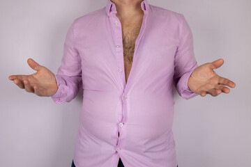 A middle aged slightly over weight man in a pink shirt that is now too small due to the man putting on weight and needed to go on a diet, time for a diet concept.