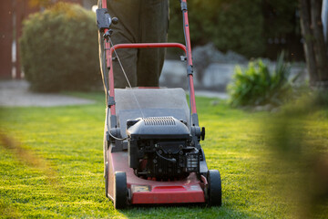 Garden worker with lawn mover. Garden works in spring.