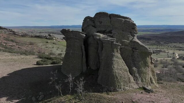 Spinning aerial drone view of a rounded red sandstone rock with an isolated Zafra castle at the back. Guadalajara, Spain. 4K
