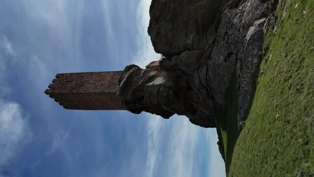 Aerial drone vertical view of the tower of a castle built in the top of a rocky hill. Vertical shot. Daylight.