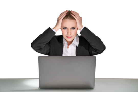 A stressed businesswoman with hands on head in front of a laptop, isolated on a white background, depicting workplace stress