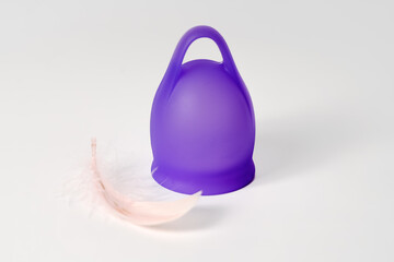 Violet Menstrual Cup Next to a Delicate Feather: Embodying Lightness