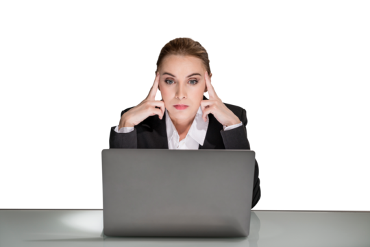 A woman in a business suit sitting at a desk with her laptop, looking stressed against a white background