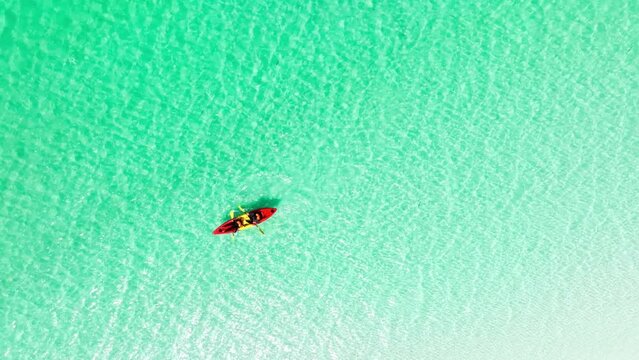 Aerial view of a woman and a young man kayaking on clear blue waters at Andaman Island. She does water sports activities.