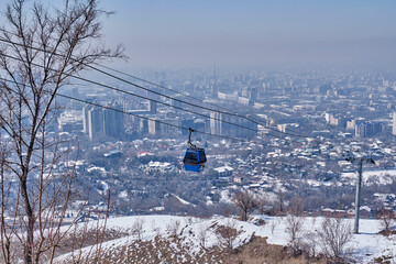 Blue cabin of cable car to Mount Kok Tobe, landmark of Almaty, Kazakhstan. Cityscape in early spring