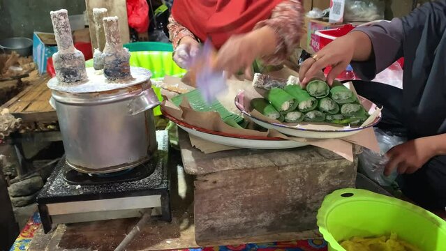 A seller prepare for Putu, Indonesian traditional snack. Made from steamed rice flour with grated coconut topping and wrapped with banana leaf.