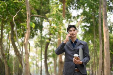 Handsome young businessman talking on mobile phone while standing at urban park