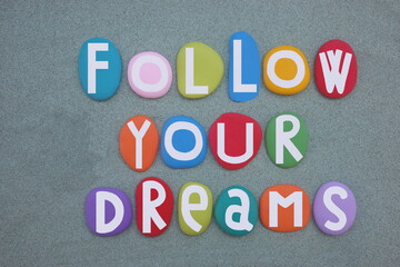 Follow your dreams, motivational and creative slogan composed with multi colored stone letters over...