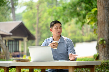 Portrait of asian man entrepreneur drinking coffee and working with laptop at outdoor