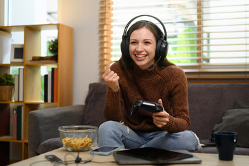 Happy young woman with joystick celebrating victory in online video game