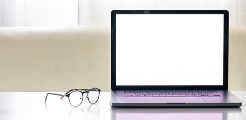 Laptop with a blank screen on a white table with a glasses.