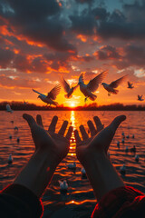 Open hands release doves into the sky at sunset, symbolizing freedom and peace, against the backdrop of a serene lake with warm hues in the sky.
