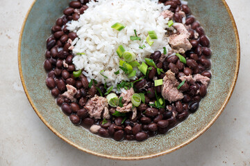 Cuban-style black beans with rice and chicken meat served in a rustic plate, horizontal shot, middle closeup, selective focus