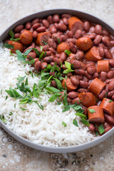 Plate of red beans with sausages and white rice, vertical shot, middle close-up, selective focus