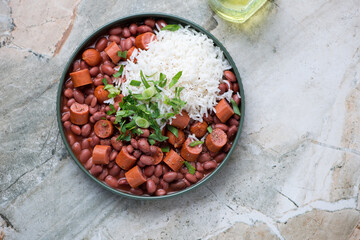 Green plate with red beans and rice on a light-grey granite background, horizontal shot with space, above view