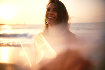 A delightful smiling woman with sun flare lighting up the beach scene