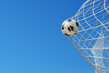  Soccer ball in soccer goal net in a big stadium isolated on blue sky. soccer net.