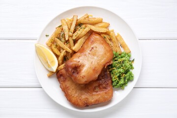 Tasty fish, chips, peas and lemon on white wooden table, top view