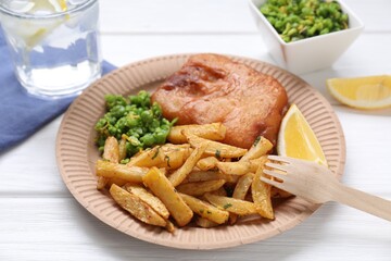 Tasty fish, chips, peas and lemon on white wooden table, closeup