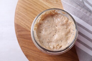 Sourdough starter in glass jar on light table, top view